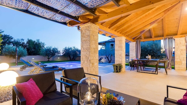 An outdoor patio with a pool, lounge chairs, a table with chairs, and a clear view of the surrounding landscape. - Villa Lyan with Swimming Pool (Tar Vabriga)