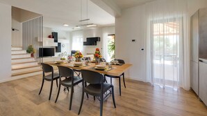 A modern dining area with a wooden table, black chairs, and a kitchen in the background. - Villa Lyan with Swimming Pool (Tar Vabriga)