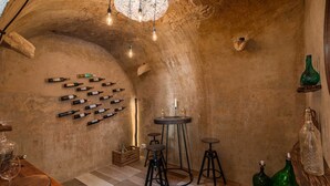 A rustic cellar with wine bottles on the wall, wooden stools, and a chandelier. - Villa Ferna with Pool (Golaš)