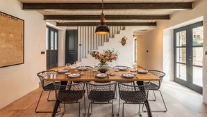 A dining area with a wooden table set for six, surrounded by black wire chairs, under a hanging light fixture. - Villa Ferna with Pool (Golaš)