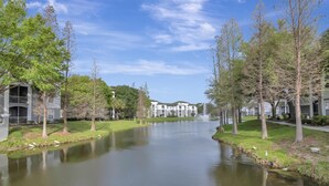 Una vista tranquila junto al río, con una fuente, árboles y edificios modernos.
