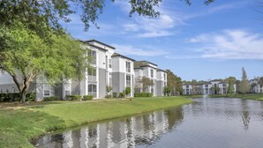 Un edificio residencial con zona verde y un estanque.