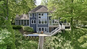 A multi-story house with a deck, surrounded by lush greenery. - Private Lakefront Escape, Launch boat from dock, swim island, hot tub, game room (Berrien Springs)