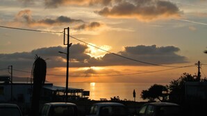 A sunset over a coastal area with buildings and parked cars. - Kokalakis Hotel (Kos)