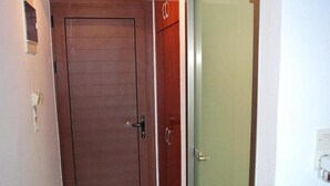 A closed wooden door with a handle and a keyhole, adjacent to a glass door with a metallic handle. - Kokalakis Hotel (Kos)