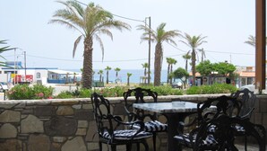 Un patio frente al mar con paredes de piedra, sillas de metal y una mesa.