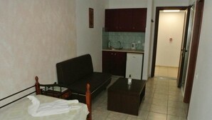 A compact room with a bed, a small sofa, a kitchenette, and a tiled floor. - Kokalakis Hotel (Kos)