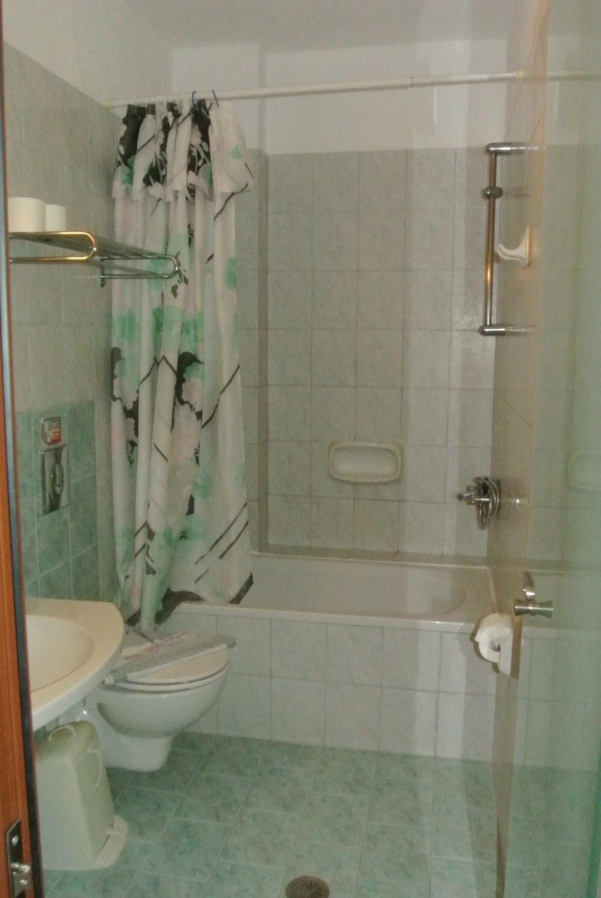 A bathroom with a toilet, a shower, and a glass-enclosed bathtub.
