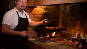Iemand barbecuet vlees in een bakstenen oven.