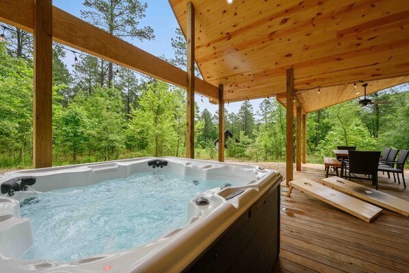 A hot tub in a wooden deck area with a view of a forest.