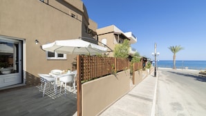 Un bâtiment situé sur la côte, doté d’une terrasse, d’une clôture en bois et offrant une vue sur la mer.