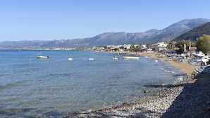 Une plage côtière avec une eau claire, des bateaux et des montagnes en arrière-plan.