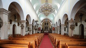 En kyrkinteriör med träbänkar, en röd matta som löper längs mittgången och en stor kristallkrona.