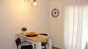 A dining area with a wooden table, two black chairs, a fruit bowl, a potted plant, and a wall clock. - Studio apartment in Štinjan with Balcony, Air condition, WIFI (5018-2) (Štinjan)