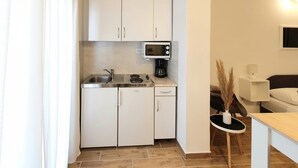 A compact kitchen with white cabinets, a microwave, a coffee maker, and a sink. - Studio apartment in Štinjan with Balcony, Air condition, WIFI (5018-2) (Štinjan)