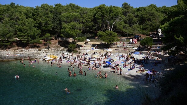 A crowded beach with people swimming and sunbathing, surrounded by trees and a rocky shoreline. - Studio apartment in Štinjan with Balcony, Air condition, WIFI (5018-2) (Štinjan)