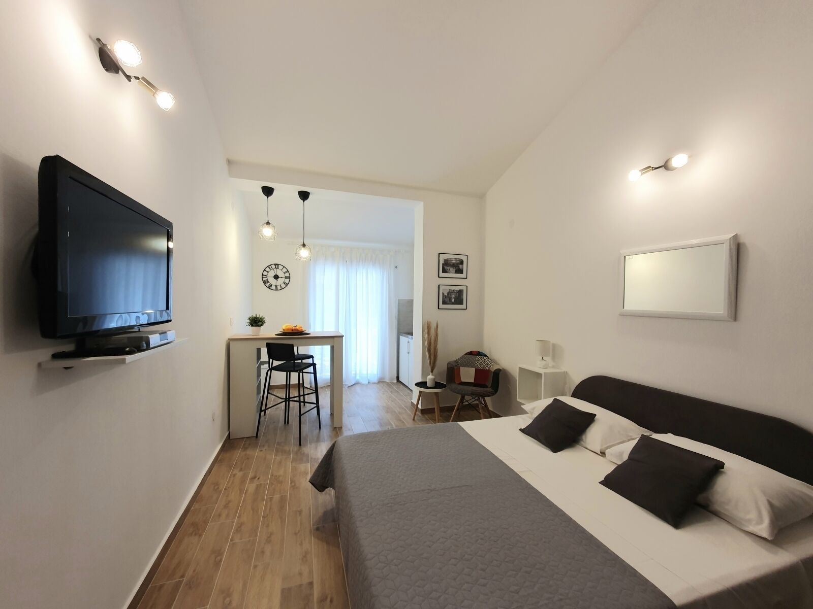 Une chambre d’hôtel moderne équipée d’un lit, d’une télévision, d’un bureau avec une chaise et d’un coin repas.