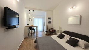 A modern hotel room with a bed, a TV, a desk with a chair, and a dining area. - Studio apartment in Štinjan with Balcony, Air condition, WIFI (5018-2) (Štinjan)