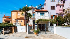 A residential building with a gated entrance, solar panels, and a palm tree. - Studio apartment in Štinjan with Balcony, Air condition, WIFI (5018-2) (Štinjan)