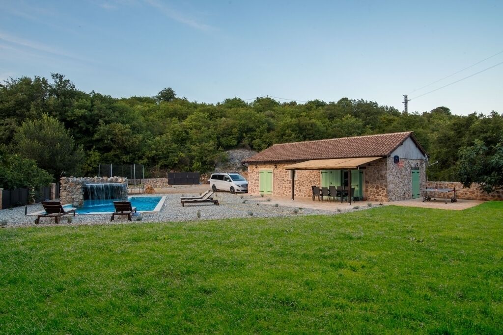 Ein Haus mit Schwimmbad, Wasserfall und Rasen.