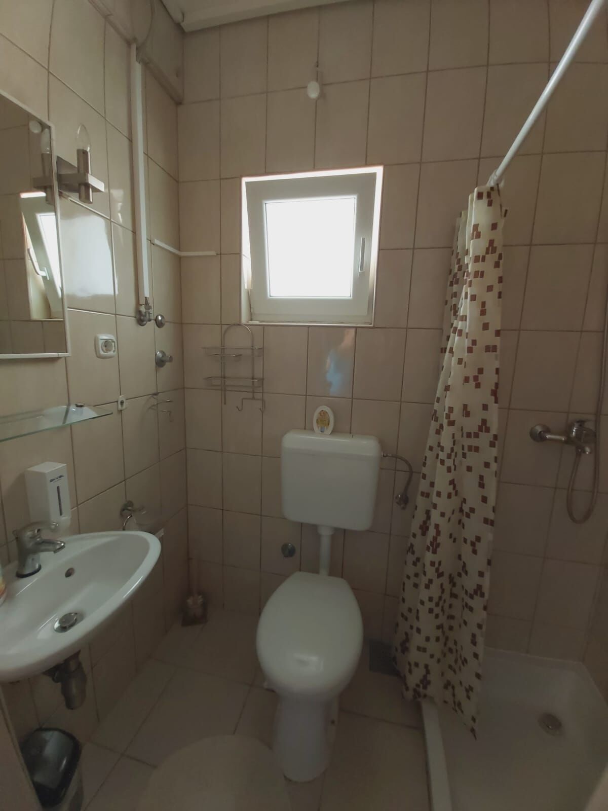 A small bathroom with a toilet, sink, and shower.