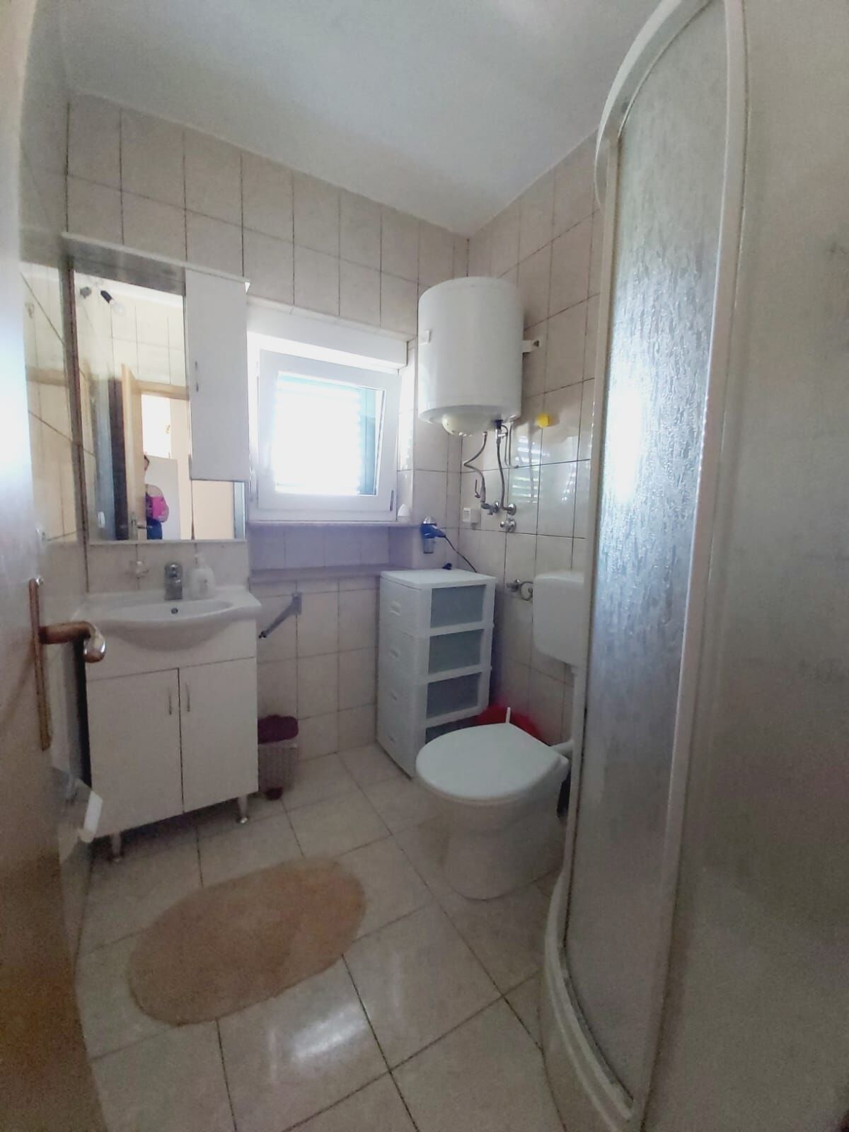 Ein Badezimmer mit Waschbecken, Spiegel, Toilette und Fenster.