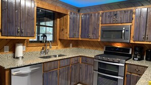 A kitchen with wooden cabinets, granite countertops, stainless steel appliances, and a window with a view. - Lakeside Retreat: Explore 35 acres of wilderness and private lake, hot tub (Ellijay)