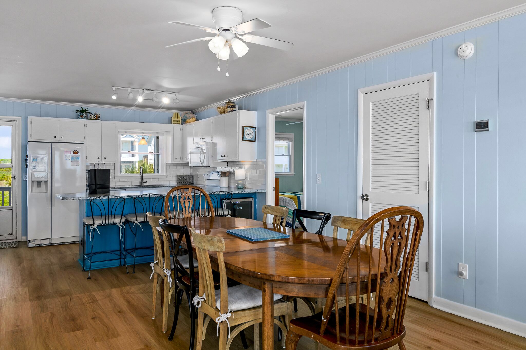 A kitchen with white cabinets, a dining table with chairs, and a ceiling fan.