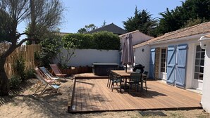 A backyard with a wooden deck, outdoor furniture, and a covered seating area. - Family vacation home with beach and spa (Barbâtre)