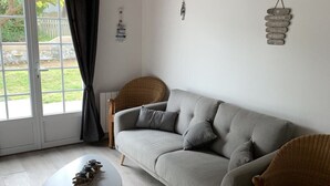 A living room with a grey sofa, two wicker chairs, a small white table, and a wooden ceiling. - Family vacation home with beach and spa (Barbâtre)