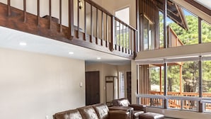 A spacious living room with a leather sectional sofa, a wooden coffee table, and a staircase leading to an upper level. - Peaceful Forest Retreat· Hot Tub · Sauna · Views (Flagstaff)