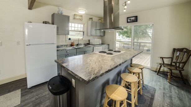 A modern kitchen with a large island, bar stools, and a view to the outside. - The Old Farmstead (Stevensville)