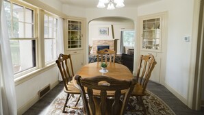 A dining area with a wooden table and chairs, a chandelier, and a fireplace. - The Old Farmstead (Stevensville)