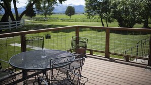 A deck with a round metal table and chairs, surrounded by a wooden railing. - The Old Farmstead (Stevensville)