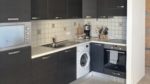 Moderni keittiö, jossa on tummat kaapit, sisäänrakennettu pesukone ja Bosch-uuni.
