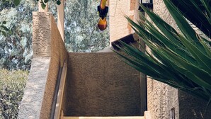 Eine Treppe führt zu einem Gebäude mit einer strukturierten Wand und einer hängenden Leuchte.