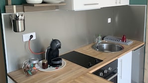 Een kleine keuken met een houten aanrecht, een koffiezetapparaat, een spoelbak en een wit kastje erboven.