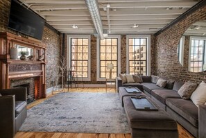 Un salon avec une cheminée, un grand canapé et un téléviseur fixé au mur.