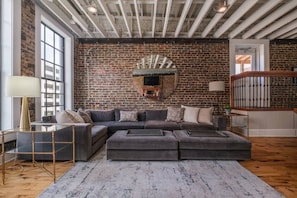 Un salon moderne avec un canapé d’angle, une cheminée et une grande fenêtre.
