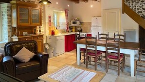 A cozy kitchen with wooden beams, a dining area with a table and chairs, and a stone wall. - A tranquil setting with beautiful views (Abjat-sur-Bandiat)