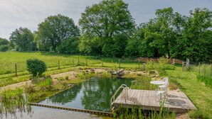 A wooden dock extending over a pond with a small bridge, surrounded by lush greenery and trees. - A tranquil setting with beautiful views (Abjat-sur-Bandiat)