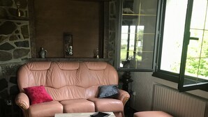 A cozy living room with a stone wall, a leather sofa, and a wooden coffee table.