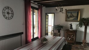 A room with a bed, a clock, a painting, a plant, and a window with curtains.