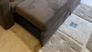 Um sofá modular cinzento com cama auxiliar, acompanhado por almofadas estampadas.