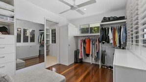 Un dressing accessible sans porte, doté d’un ventilateur de plafond et d’une fenêtre donnant sur un paysage verdoyant.