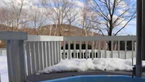 A hot tub with a wooden deck and a snowy landscape in the background. - Clean, quiet and cozy mountain get away Condo (Bartlett,)