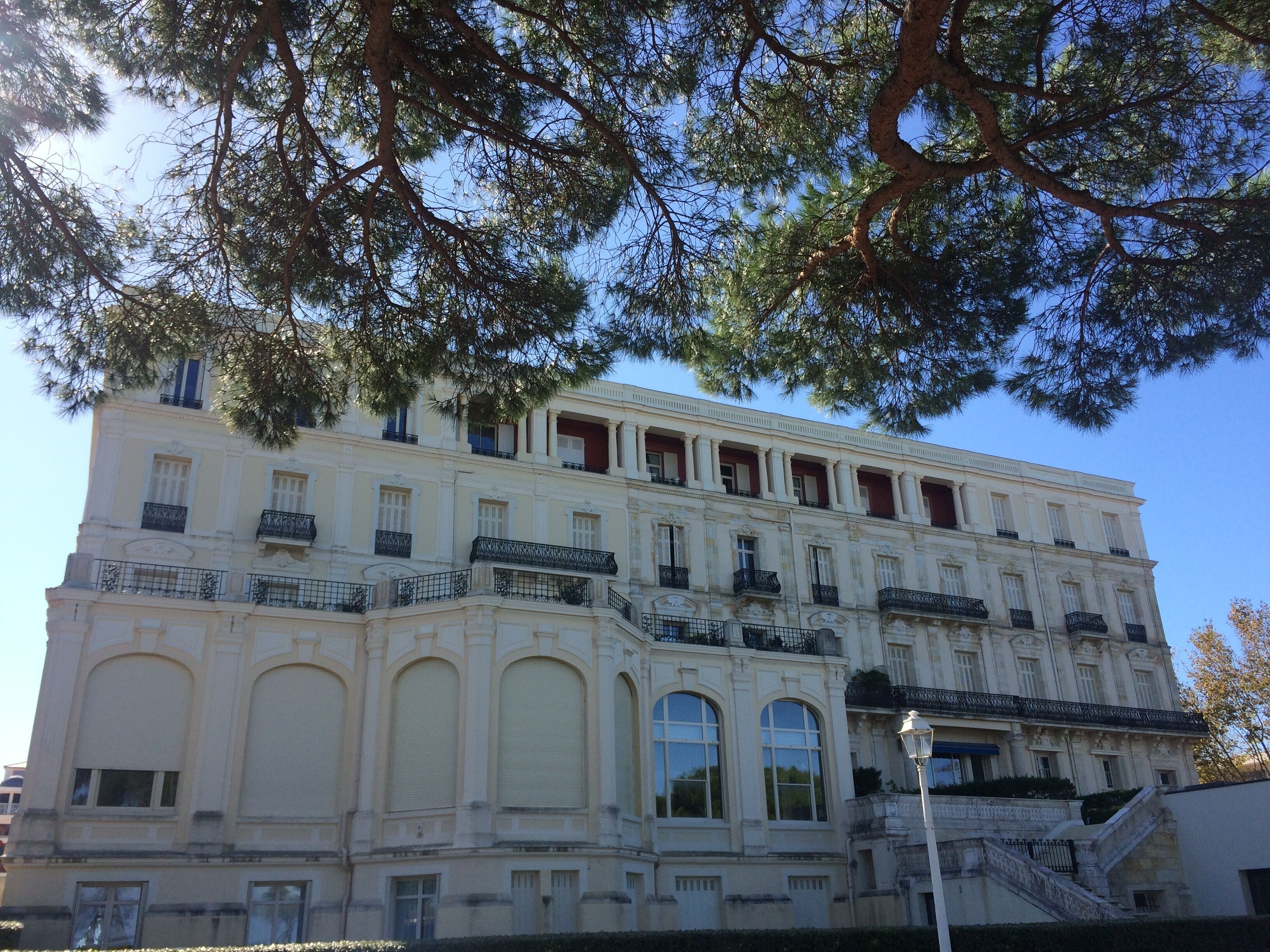 Un bâtiment historique doté de nombreux balcons et de grandes fenêtres, qui pourrait être un hôtel ou un bâtiment public.