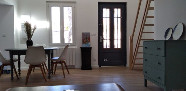 Una habitación con una mesa de comedor, sillas, una puerta negra, un radiador y un aparador.