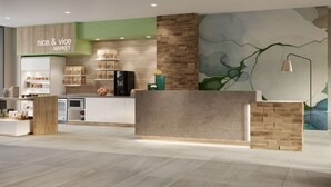 A modern reception area with a counter, a wall-mounted lamp, and a mural.