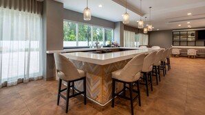 A modern kitchen with a central island, bar stools, and pendant lighting.